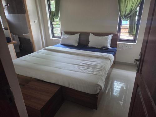 a small bed in a room with two windows at Evergreen Service Apartments in Kottakkal