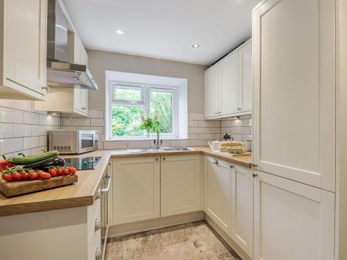 a kitchen with white cabinets and a bowl of fruit on the counter at Lane Ends Cottage in Disley