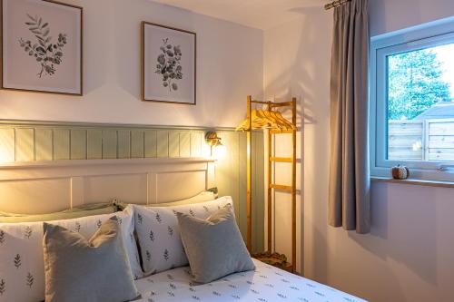 a bedroom with a bed with pillows and a window at The Perk Inn Garden Lodge in Broadstone