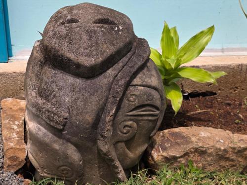 a statue of a person sitting next to a plant at La Maison de l'Artiste in Hauru