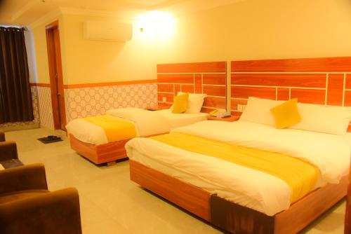 Habitación de hotel con 2 camas con sábanas blancas y amarillas en Bless-Inn & Restaurant, en Islamabad