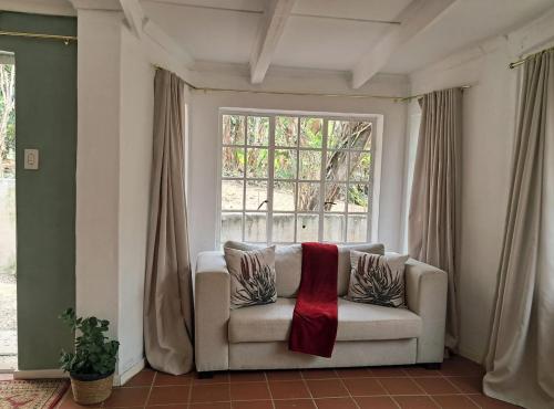 Una sala de estar con un sofá y una ventana. en The Hide Guesthouse Pietermaritzburg Self-catering, en Pietermaritzburg