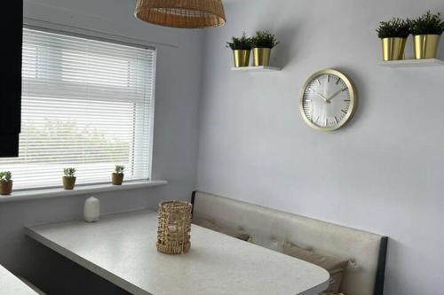 a room with a table and a clock on the wall at 4-Bed House - Sea View Garden Parking Wifi in Portstewart