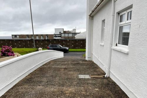 a car parked next to a white building at 4-Bed House - Sea View Garden Parking Wifi in Portstewart