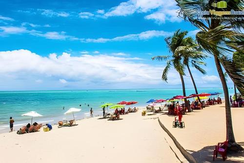 people on a beach with umbrellas and the ocean at Apê 100 metros do mar - Praia in Maceió