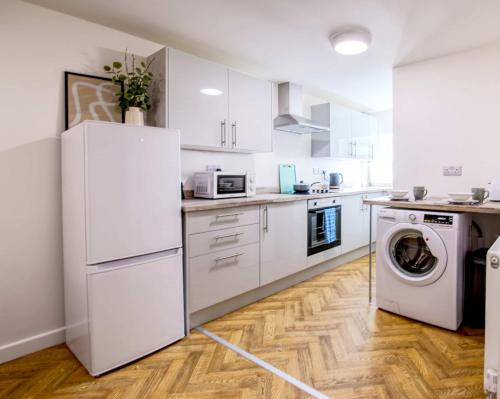 a kitchen with white cabinets and a washer and dryer at NEW Contractor 5-Bed 3-Bath Central Redcar in Redcar