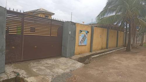 a fence with a wooden gate and a fence with a sign on it at Zehra Lodge & Gardens in Ikorodu