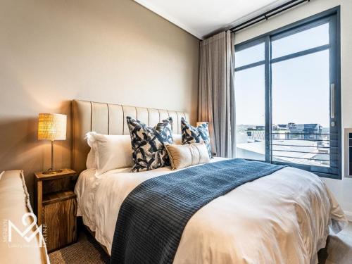 a bedroom with a bed with a large window at Menlyn Maine Luxury Rentals in Pretoria