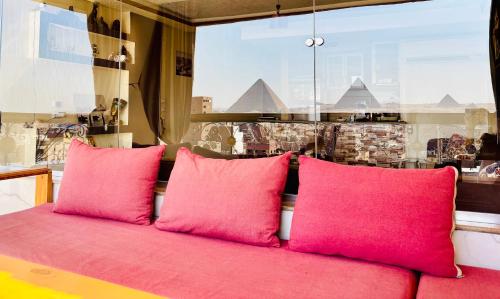a red couch with pink pillows in front of a window at Isis Guest House in Cairo
