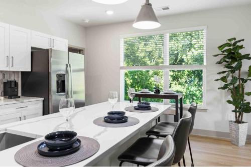 a kitchen with a counter with chairs and a table at Pristine Living 5 Min From Downtown in Wilders Grove