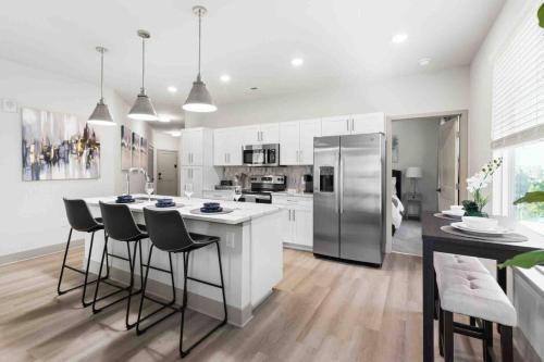 a kitchen with white cabinets and a kitchen island with bar stools at Pristine Living 5 Min From Downtown in Wilders Grove