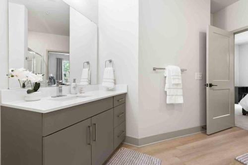 a white bathroom with a sink and a mirror at Pristine Living 5 Min From Downtown in Wilders Grove