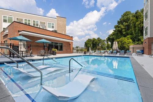 a swimming pool with white chairs and a building at Stunning Living 5 Min From Downtown in Wilders Grove