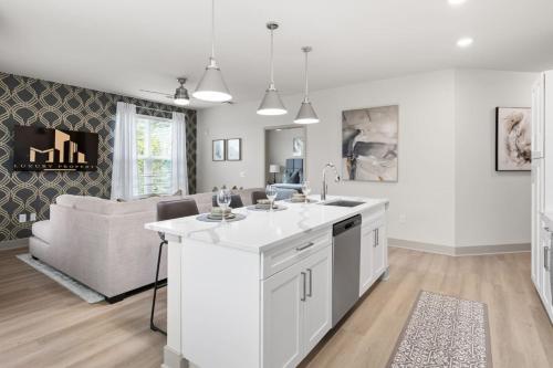 a kitchen and living room with white cabinets and a couch at The Icon 5 Min From Downtown in Wilders Grove