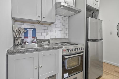 a kitchen with white cabinets and a stainless steel refrigerator at 2 BD Tranquil Unit close to Central Park in New York