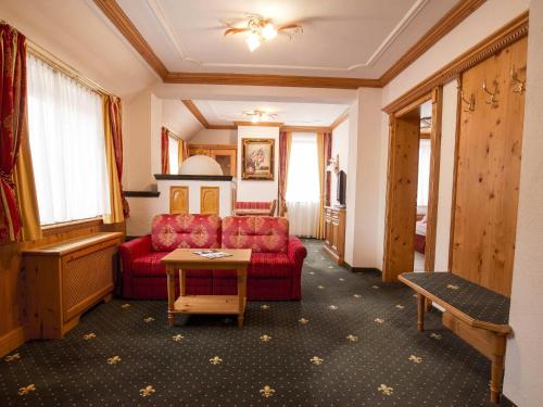 a hotel room with a red couch and a table at Mercure Sighisoara Binderbubi Hotel & Spa in Sighişoara