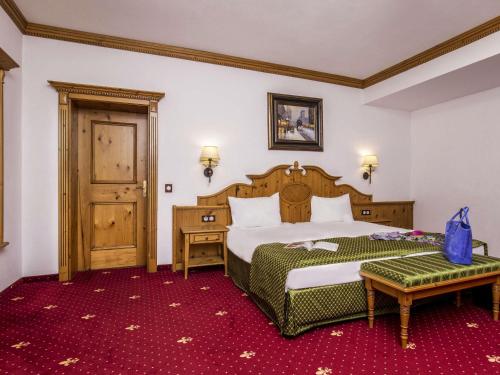 a hotel room with a bed and a table at Mercure Sighisoara Binderbubi Hotel & Spa in Sighişoara