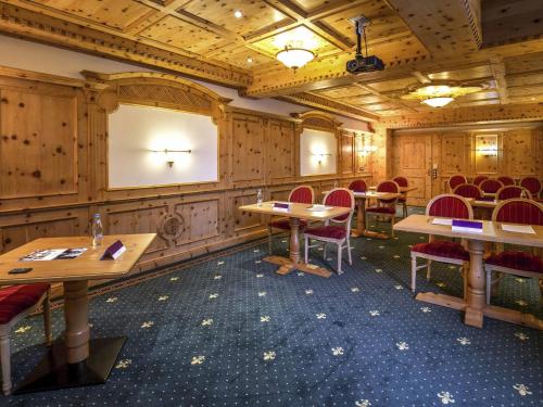 a conference room with tables and chairs and a screen at Mercure Sighisoara Binderbubi Hotel & Spa in Sighişoara