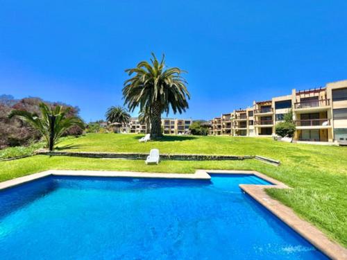 MAITENCILLO VISTA BOSQUE y MAR في مايتنسيلو: مسبح امام عمارة سكنية