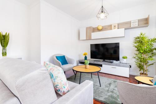 a living room with a white couch and a tv at Carmo Lookout in Câmara de Lobos