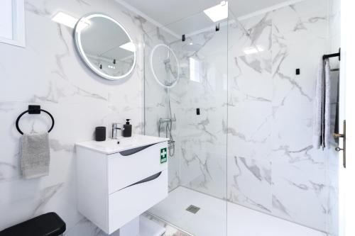 a white bathroom with a shower and a sink at Carmo Lookout in Câmara de Lobos