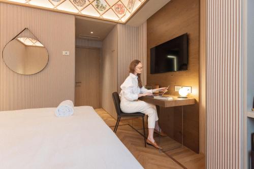 a woman sitting at a desk in a hotel room at QC Room Milano Porta Romana in Milan