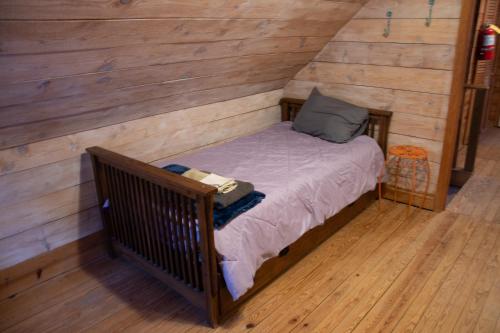 a small bed in a room with wooden walls at Project Chimps Historic Cabin in Morganton