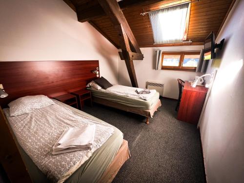 a bedroom with two beds and a desk with a window at Hotel Chalet du Crey in Valmorel