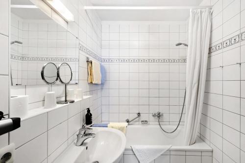 ein weißes Badezimmer mit Badewanne und Waschbecken in der Unterkunft Fewo Brünnstein - Nr 44 Pool, Sauna in Oberaudorf