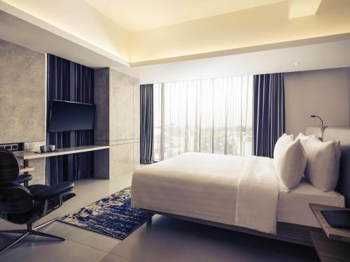 a hotel room with a bed and a desk and a television at Mercure Bandung City Centre in Bandung