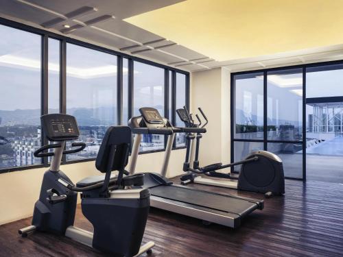 a gym with cardio equipment in a building with windows at Mercure Bandung City Centre in Bandung