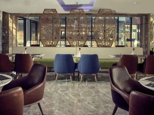 a restaurant with chairs and a table and a bar at Mercure Bandung City Centre in Bandung