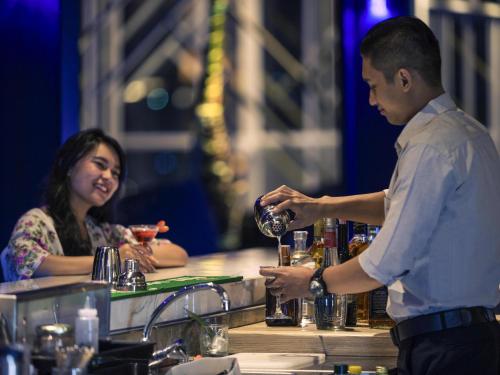 a man pouring a woman a drink at a bar at Mercure Bandung City Centre in Bandung