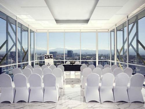 a room with white chairs and a table with a view at Mercure Bandung City Centre in Bandung