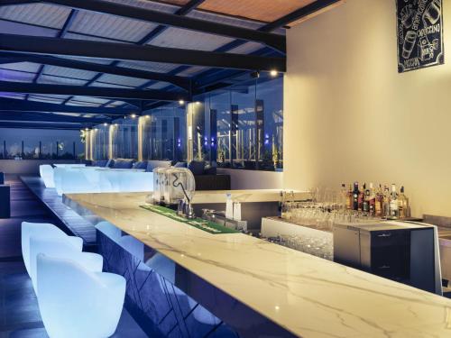 a bar with white stools and alcohol bottles at Mercure Bandung City Centre in Bandung
