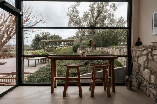 a table and two stools in front of a large window at MANEJ URLA in Izmir