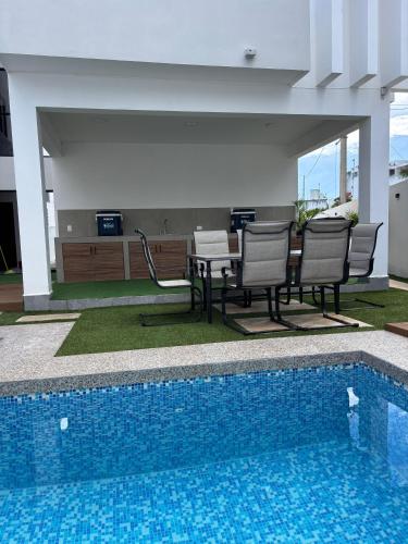 a swimming pool with chairs and a table next to a house at Privada Huayacan in Cancún