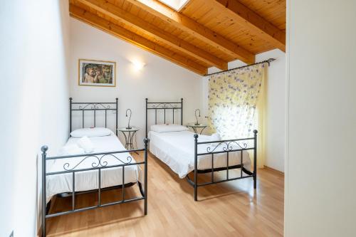 two beds in a room with wooden ceilings at Agriturismo Al Tralcio in Valeggio sul Mincio