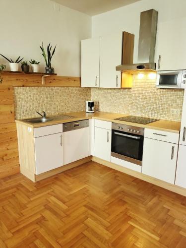 Eine Küche mit weißen Schränken und Holzboden in der Unterkunft Pine House in Fürstenfeld