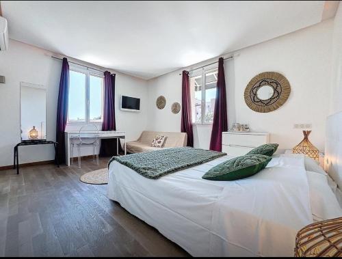 a bedroom with a large white bed and a desk at Hôtel Les 3 Terrasses in Sari Solenzara