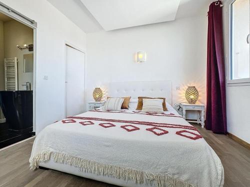 a white bedroom with a large bed with red accents at Hôtel Les 3 Terrasses in Sari Solenzara