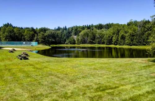 a park with a lake and a grass field at Vermont Escape near Stratton with Hot Tub, Game Room, Fireplace & Pond Views in Strattonwald