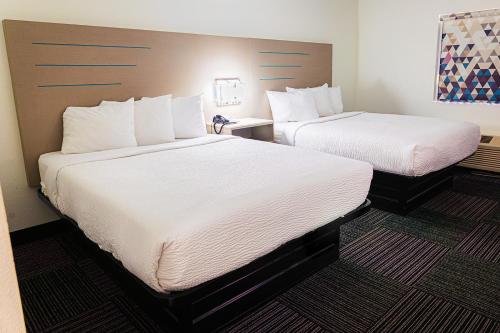 two beds in a hotel room with white sheets at Baymont by Wyndham Port Wentworth in Port Wentworth