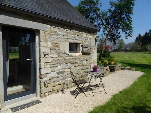 un edificio de piedra con mesa y sillas al aire libre en Gîte Clos St Roch, en Combrit