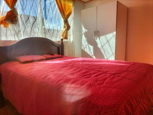 a bedroom with a large red bed with a window at Home in Tulcán