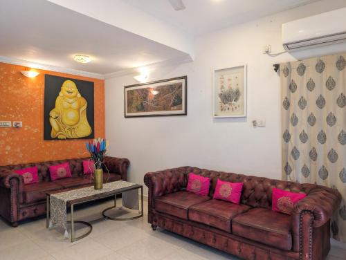 a living room with two brown couches and pink pillows at Villa Candolim in Candolim