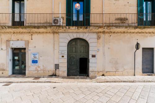 a building with a black door and a balcony at Piazzetta San Giovanni Specchia in Specchia