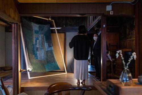 a woman standing in a room looking at a painting at Sokuan a 120 Year Old Art Filled Inn in Yui