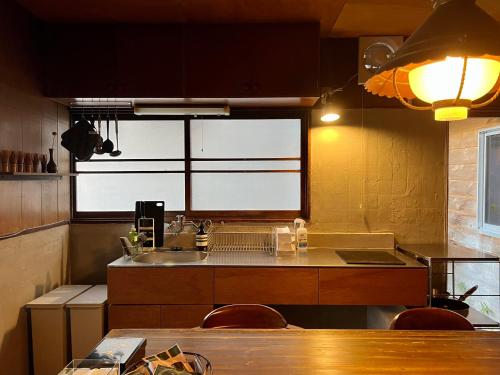 a kitchen with a sink and a table with chairs at Sokuan a 120 Year Old Art Filled Inn in Yui