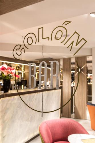 a restaurant with a red chair and a sign that reads colony bar at NH Collection Madrid Colón in Madrid